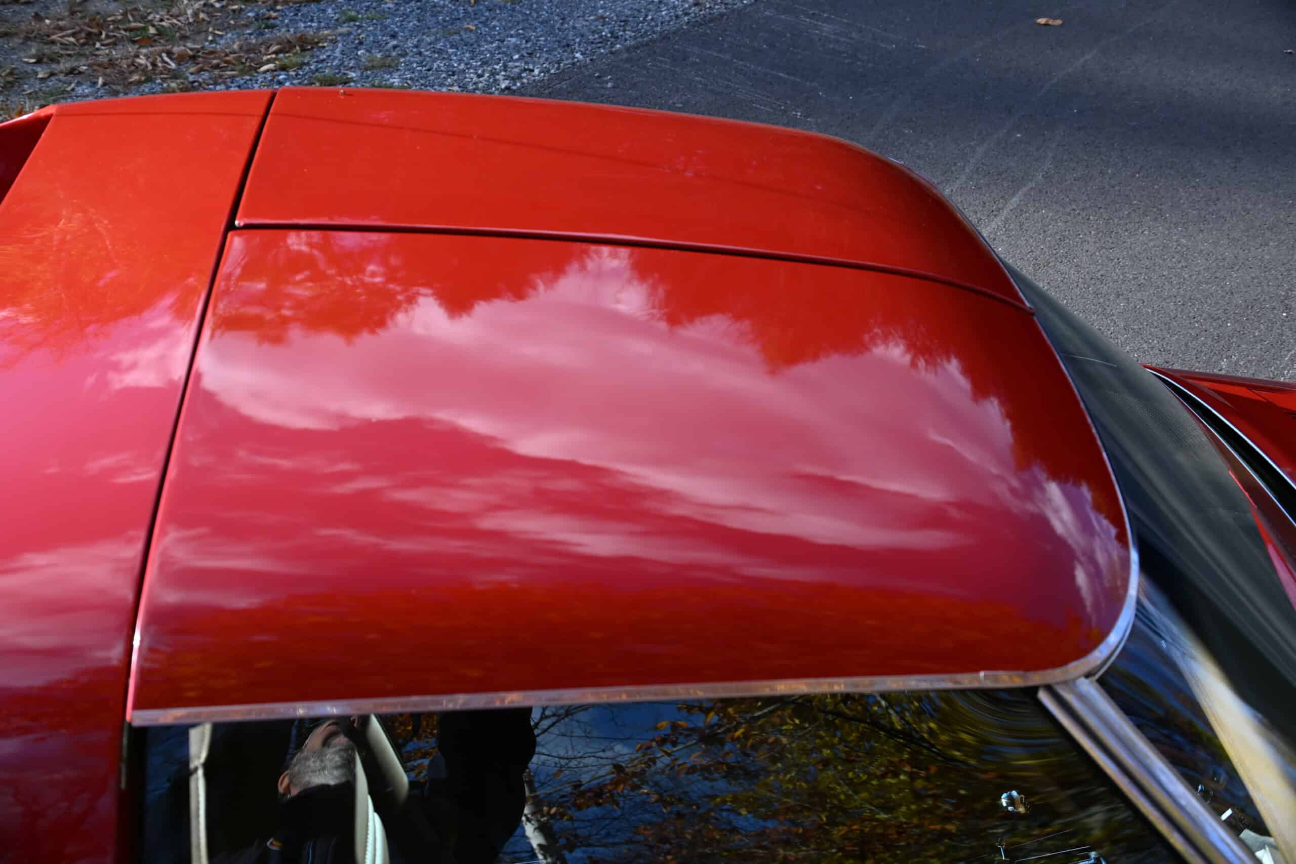1972 Chevrolet corvette — Close-up of classic car roof with red paint and reflections.