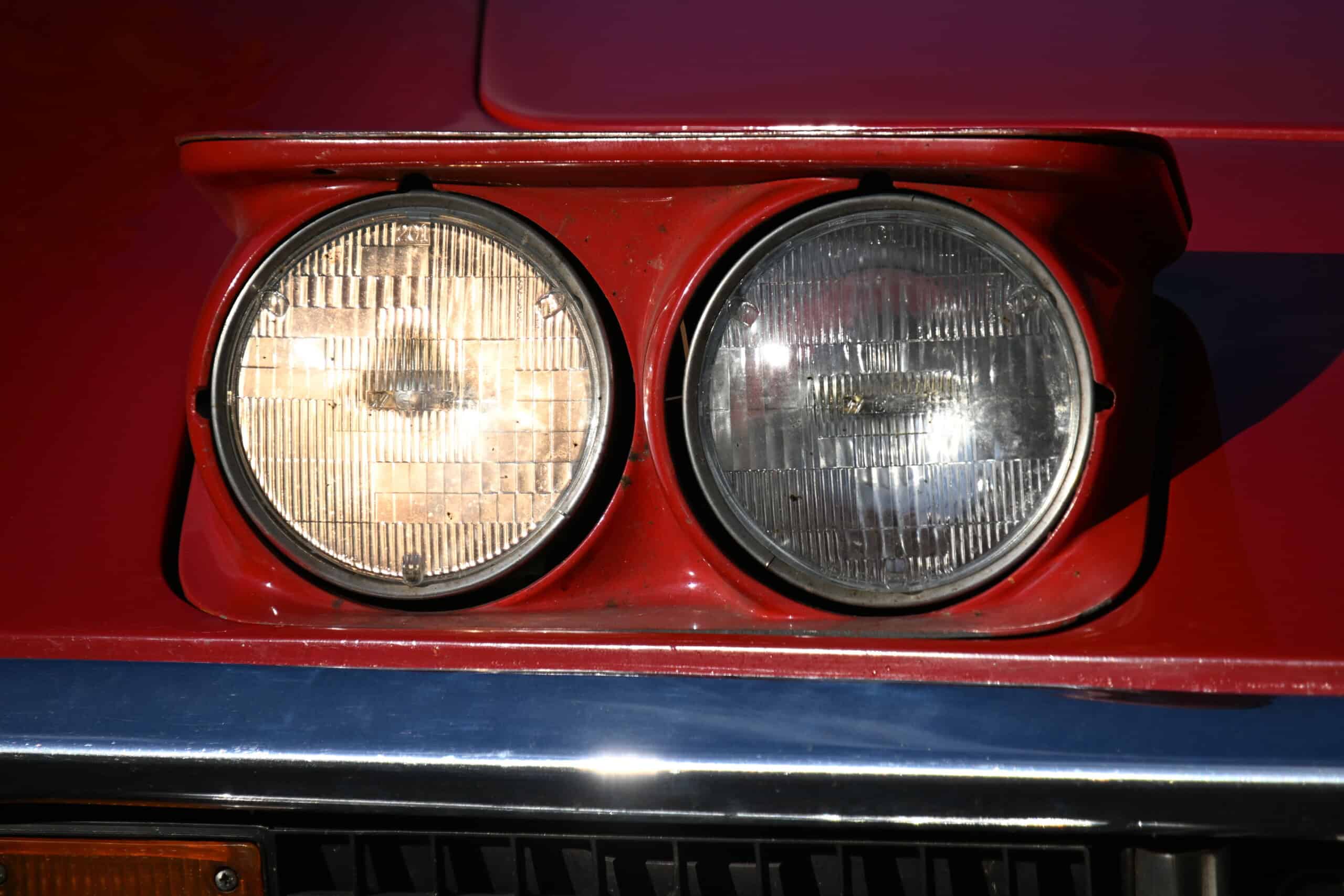 1972 Chevrolet corvette — Close-up of classic car headlights on red body with chrome bumper.