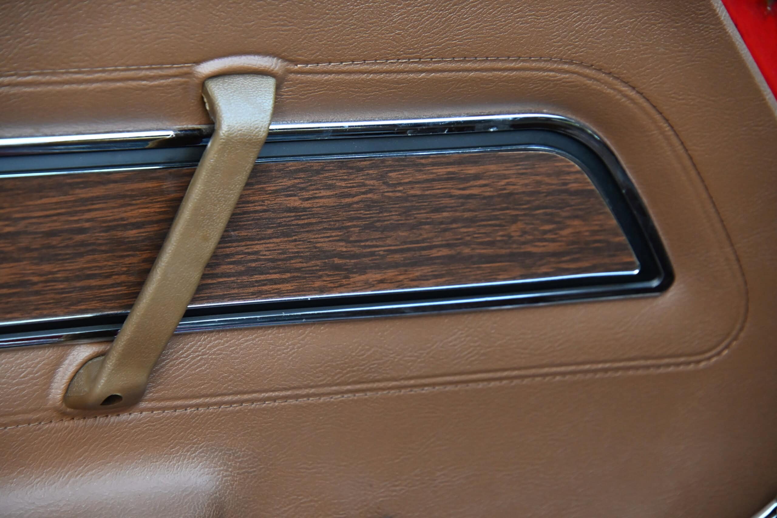 1972 Chevrolet corvette — Close-up of classic car interior door with wood trim and handle.