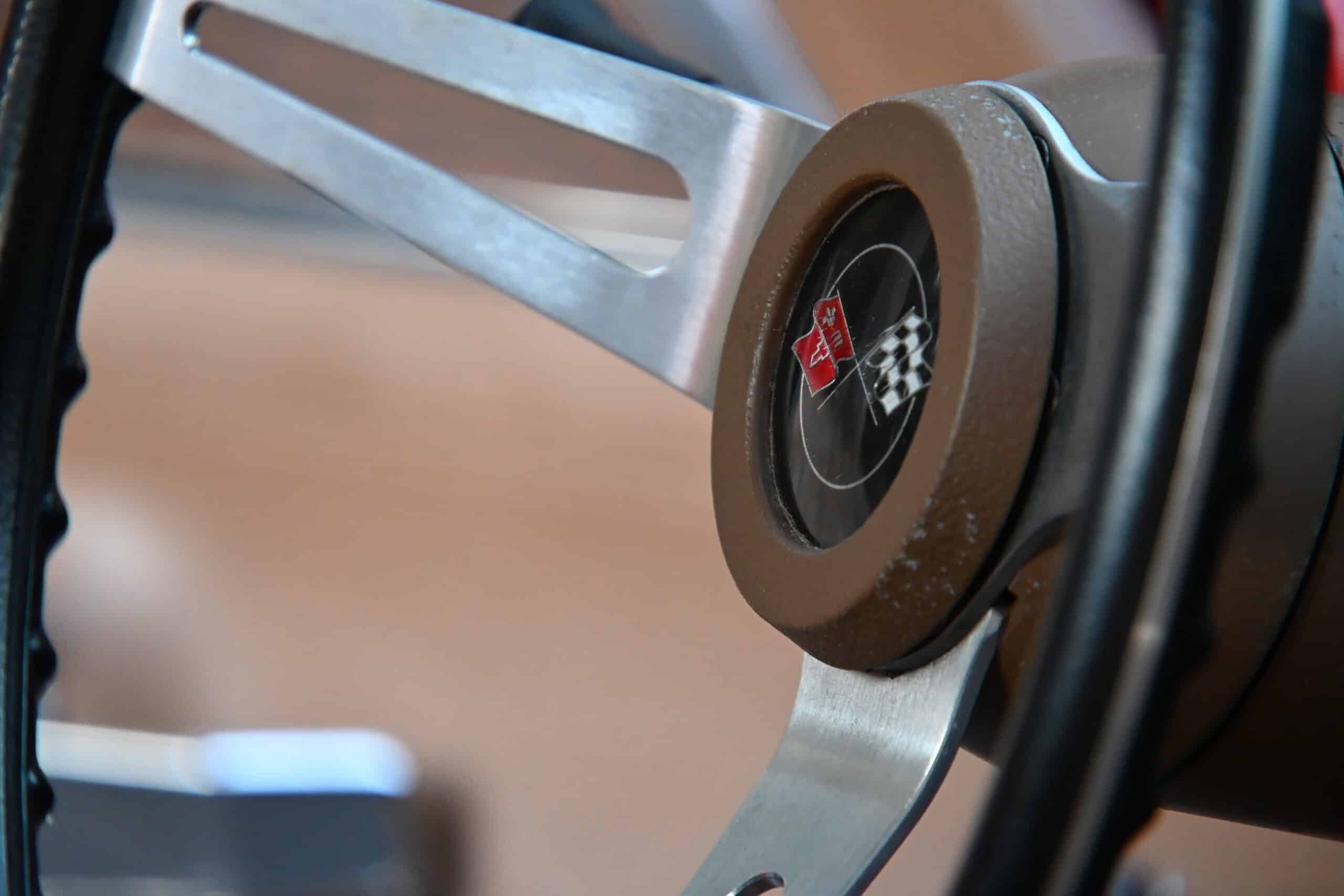 1972 Chevrolet corvette — Close-up of classic car steering wheel with emblem and checkered flag.