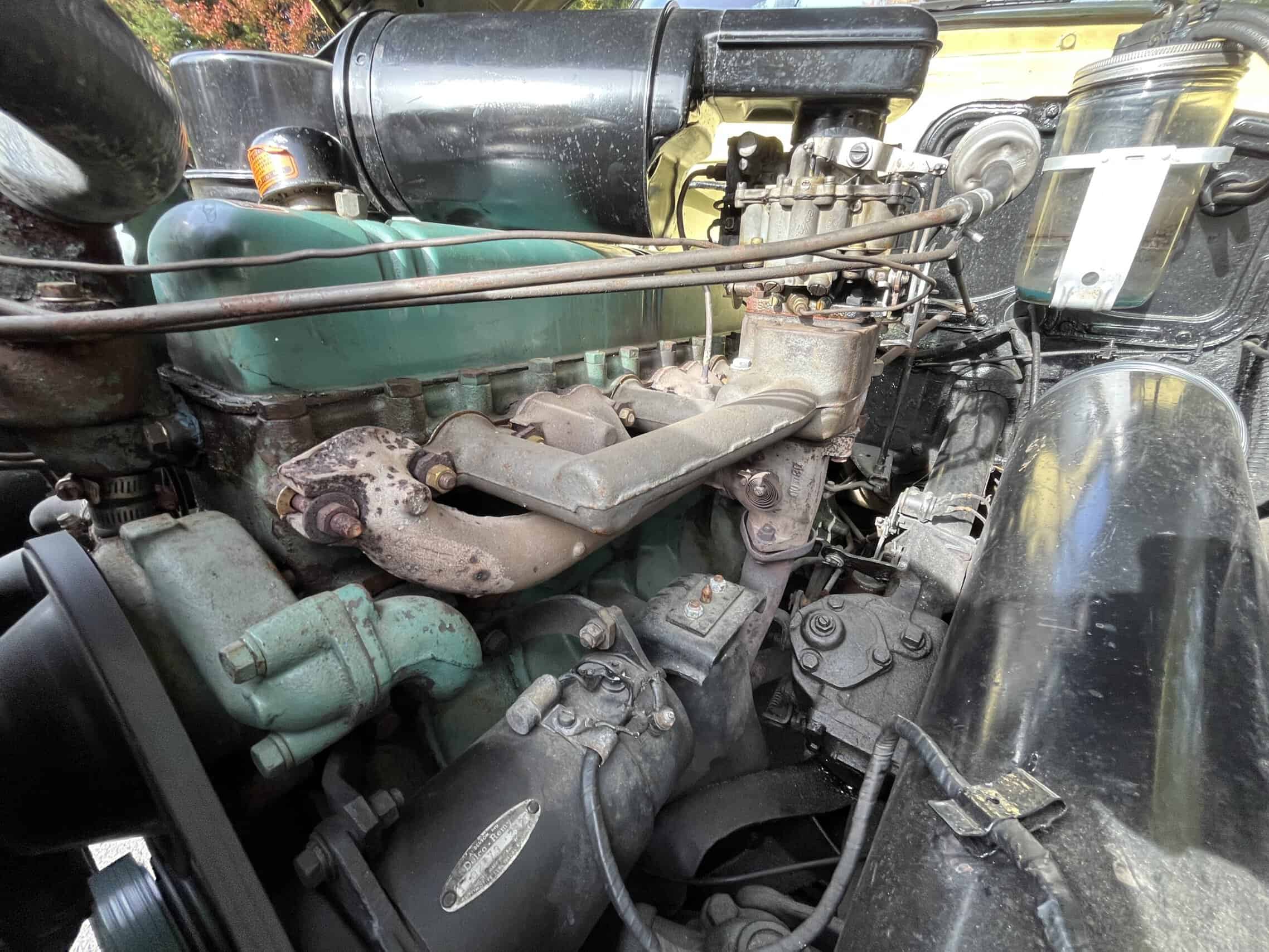 1953 Buick special — Close-up of a vintage car engine with visible components and pipes.